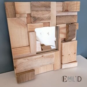 Miroir avec cadre en bois recyclé, présentant un motif mosaïque unique, accroché au mur d'une pièce lumineuse.