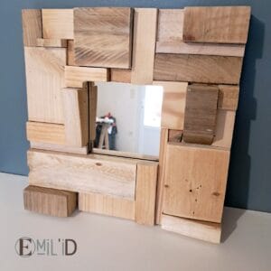 Miroir avec cadre en bois recyclé, présentant un motif mosaïque unique, accroché au mur d'une pièce lumineuse.